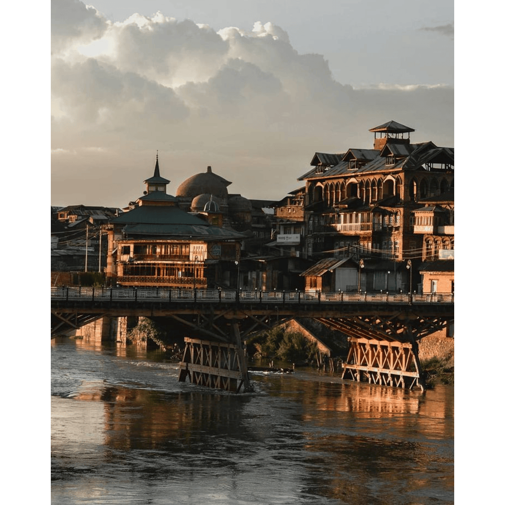 A scenic view of Downtown Srinagar, showcasing its bustling streets, traditional Kashmiri architecture, and the backdrop of the majestic Himalayan mountains